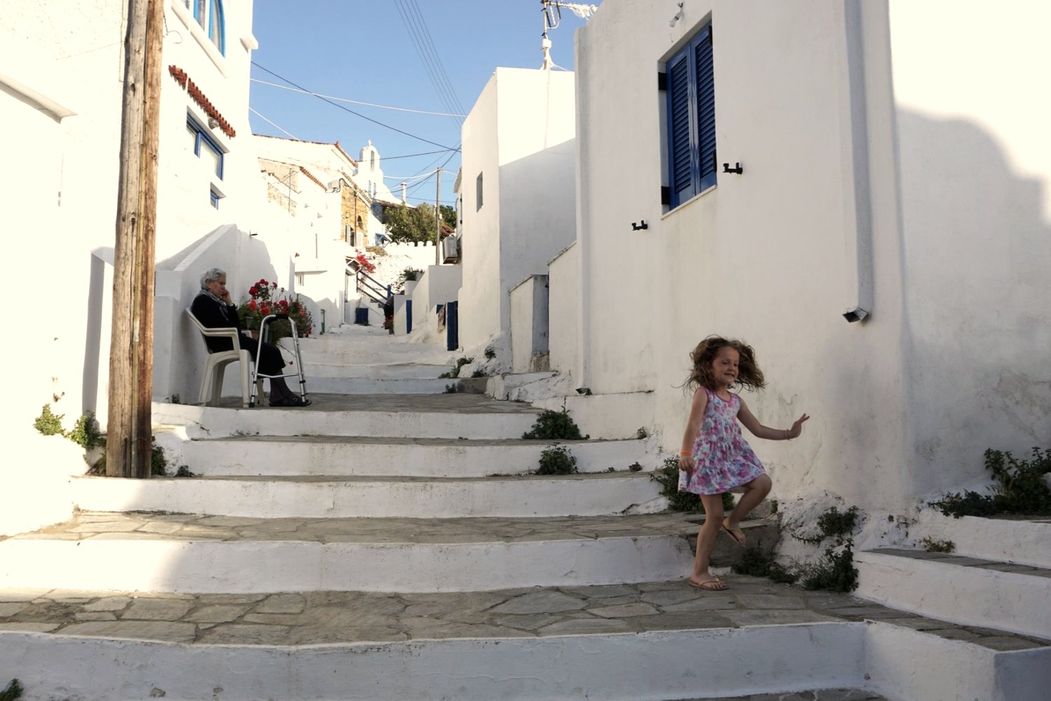 A whitewashed alley in Dryopida, Kythnos, with blue railings and stone steps