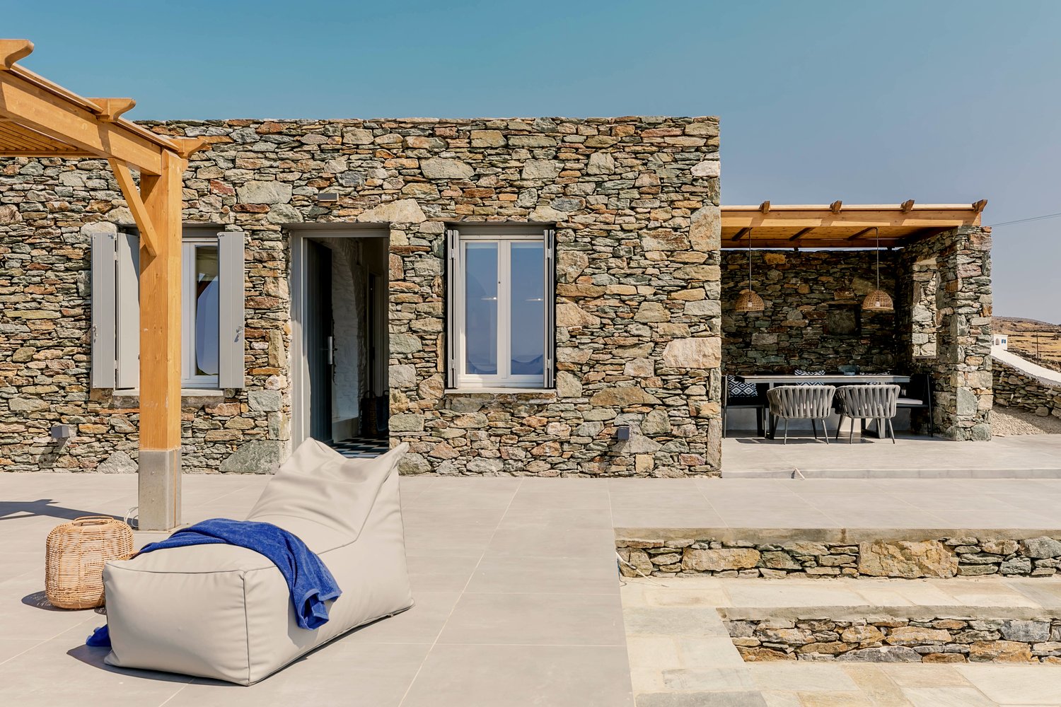 The whitewashed Cycladic stone exterior of Verros Hut with its wooden pergola